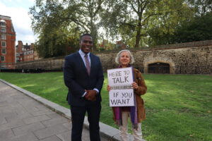 Livia and Jeremiah stand together. Livia holds her sign.